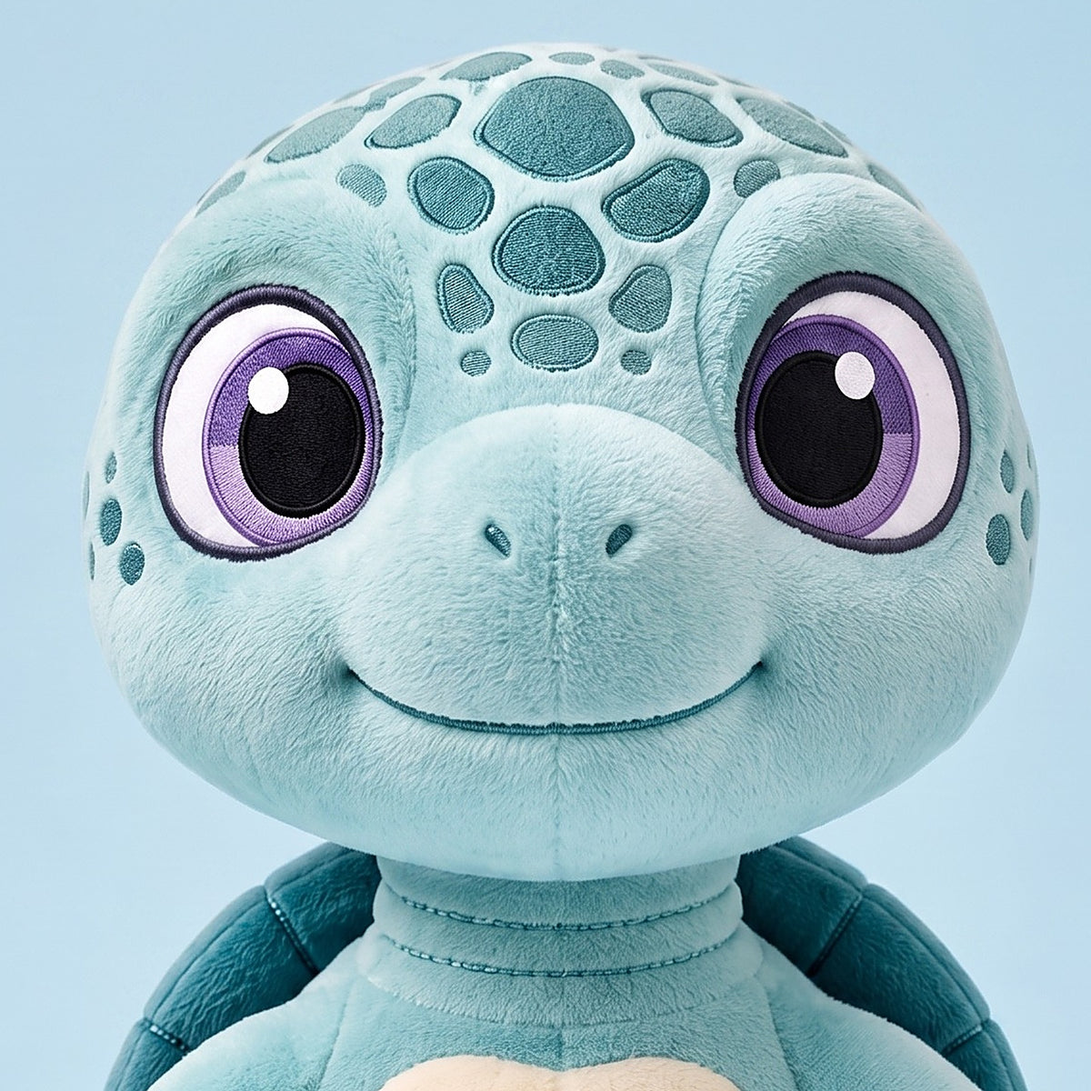 Close-up of the Eli plush face, embroidered purple eyes and seafoam shell