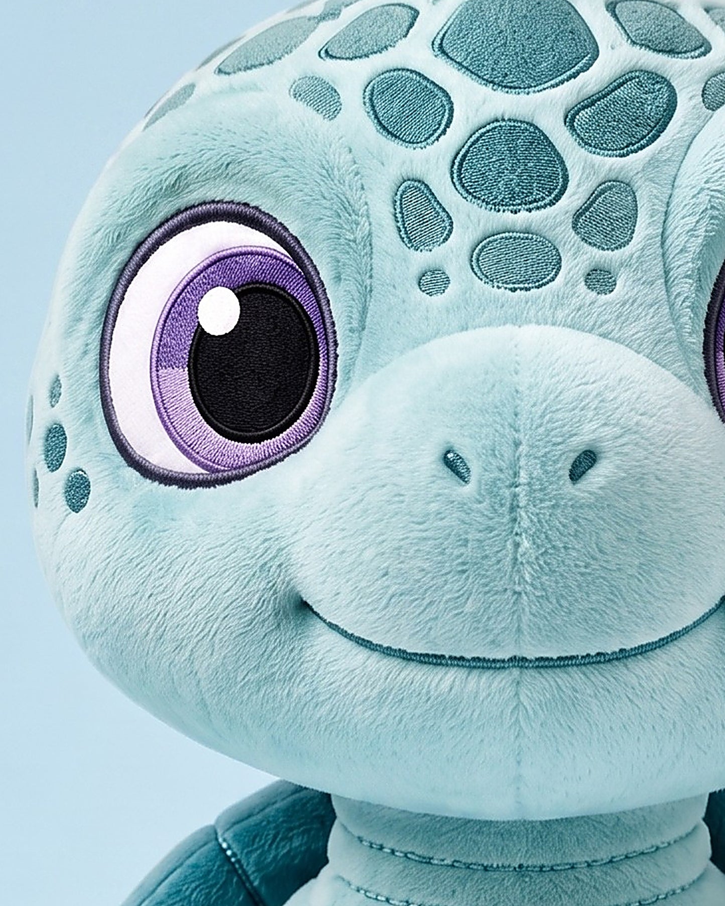 Macro detail of the embroidered stitching on the Eli plush shell and eye